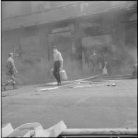 Alger. Quartier des Tagarins. Explosion d'un camion-citerne. Des soldats, des civils et un pompier sortent des bouteilles de gaz d'un immeuble.