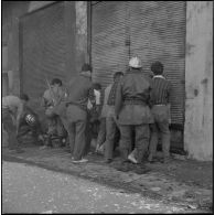 Alger. Quartier des Tagarins. Explosion d'un camion-citerne. Des soldats, des civils et des pompiers ouvrent les grilles d'un immeuble où des bouteilles de gaz sont stockées.