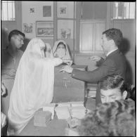 Journée de vote pour le référendum d'autodétermination (1er juillet 1962). Une femme glisse son bulletin de vote dans l'urne face à un assesseur du bureau de vote n°1.