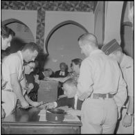 Journée de vote pour le référendum d'autodétermination (1er juillet 1962). Des assesseurs vérifient les identités des votants à l'intéieur d'un bureau de vote.