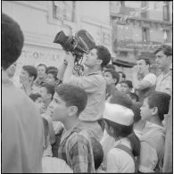 Journée de vote pour le référendum d'autodétermination (1er juillet 1962). Un caméraman de l'Établissement cinématographique des armées (ECA) filme dans une rue avec une caméra Arriflex.
