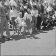 Un garçon parmi la foule brandissant un drapeau algérien pour la cérémonie de lever des couleurs algériennes.