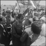 Des personnalités politiques félicitent des personnalités militaires parmi la foule.