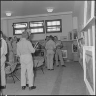 Des officiers visitent une exposition de peinture à la base aérienne 210 (BA 210).