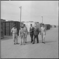 Des directeurs de l'entreprise Danzas et Tailleur marchent au milieu de containers au port d'Oran avec des militaires.