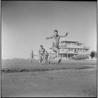 Activités sportives d'une section du 152e régiment d'infanterie (RI). Un soldat saute par dessus un courant d'eau sur la plage.