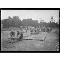 [Des soldats rangent des obus en les faisant rouler à la main sur des rails.]
