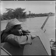 Soldat à la tourelle d'une vedette blindée du 4e régiment de dragons armée d'une mitrailleuse de 12,7 mm, au cours d'une patrouille sur la rivière de Saigon.