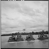 Convoi de vedettes blindées du 4e régiment de dragons survolées par un hydravion sur la rivière de Saigon. [description provisoire]
