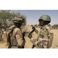 Un soldat du 501e régiment de chars de combat (RCC) contrôle le téléphone portable d'un suspect aux côtés d'un soldat nigérien de la 112e compagnie de sécurité et d'intervention (CSI) dans le Liptako, au Niger.