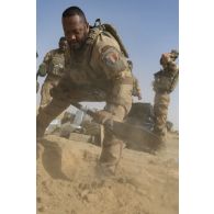 Un soldat creuse un trou pour brûler les déchets au terme d'une livraison par air dans le secteur du Liptako, au Niger.