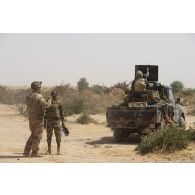Un agent du centre de mise en oeuvre influence opération (CMO-IO) se coordonne avec un chef de section nigérien de la 3e compagnie de sécurité et d'intervention (CSI) pour la caractérisation du village de Kinabay, au Niger.