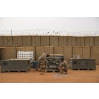 Des opérateurs du Service de l'énergie opérationnelle (SEO) manipulent la motopompe d'un réservoir souple à carburant sur la base de Gossi, au Mali.