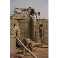 Des soldats de l'atelier chaud froid démontent un dispositif de climatisation sur une zone vie de la base de Gossi, au Mali.