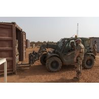 Des soldats rangent une dalle de sol à bord d'un container au moyen d'un chariot télescopique léger MLT 625 sur la base de Gossi, au Mali.