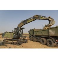 Une pelle hydraulique modèle 317 charge des déchets de chantier dans un camion-benne sur la base de Gossi, au Mali.