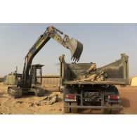 Une pelle hydraulique modèle 317 charge des déchets de chantier dans un camion-benne sur la base de Gossi, au Mali.