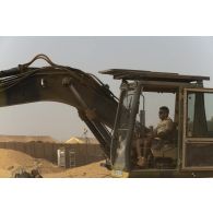 Un soldat pilote une pelle hydraulique modèle 317 sur la base de Gossi, au Mali.