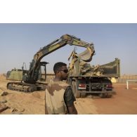 Une pelle hydraulique modèle 317 charge des déchets de chantier dans un camion-benne sur la base de Gossi, au Mali.