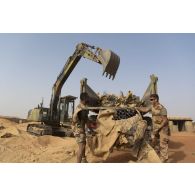 Une pelle hydraulique modèle 317 charge des déchets de chantier dans un camion-benne sur la base de Gossi, au Mali.