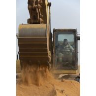 Un soldat pilote une pelle hydraulique modèle 320 sur la base de Gossi, au Mali.