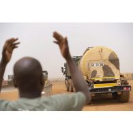 Un chauffeur civil guide le chargement d'un camion ravitailleur pétrolier de l'avant à capacité étendue (CARAPACE) du Service de l'énergie opérationnelle (SEO) à bord d'un camion semi-remorque à Gao, au Mali.