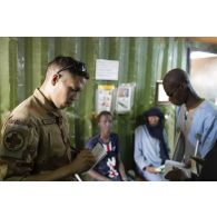Un auxiliaire sanitaire reçoit des patients civils pour leur consultation médicale à Gao, au Mali.