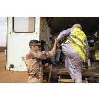 Un auxiliaire sanitaire aide un patient civil à embarquer à bord d'une ambulance pour sa consultation à Gao, au Mali.