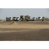 Des camions semi-remorque stationnent en colonne à l'arrêt d'un convoi sur la piste de Ménaka,  au Mali.