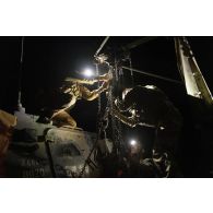 Des mécaniciens de l'élément léger d'intervention (ELI) arriment un véhicule blindé léger (VBL) au treuil d'un camion lourd de dépannage (CLD) sur une base avancée dans le secteur de Ouallam, au Niger.