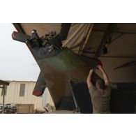 Un mécanicien aéronautique monte les pales et les carters de protection du rotor anticouple d'un hélicoptère Caïman NH-90 à Gao, au Mali.