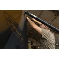 Un mécanicien aéronautique monte les pales et les carters de protection du rotor anticouple d'un hélicoptère Caïman NH-90 à Gao, au Mali.