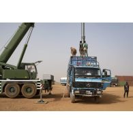 Une grue automotrice LTM 1055 décharge un container depuis un camion semi-remorque à Gao, au Mali.