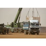 Une grue automotrice LTM 1055 décharge un container depuis un camion semi-remorque à Gao, au Mali.