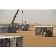 Une grue automotrice LTM 1055 et un chariot élévateur lourd (CEL) déchargent des containers depuis un camion semi-remorque à Gao, au Mali.