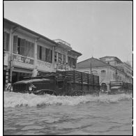 Passage d'un convoi de camions GMC dans la rue Ohier à Phnom Penh, après le passage d'un typhon. [description provisoire]