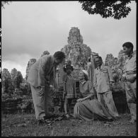 Richard Nixon, vice-président des États-Unis, et son épouse Pat Nixon posent avec une petite fille cambodgienne devant le Bayon.