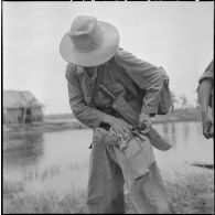 Un voltigeur du 2/43e régiment d'infanterie coloniale place un poulet dans la poche de son treillis au cours de l'opération Tourbillon VII. [description provisoire]