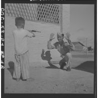 Jeu entre un soldat de la 1re compagnie du 13e bataillon vietnamien et son fils au cantonnement. [description provisoire]