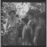 Des enfants interrogent un lieutenant commandant la 3e compagnie du 13e bataillon vietnamien de passage dans un hameau. [description provisoire]
