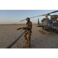Un soldat du Service de l'énergie opérationnelle (SEO) ravitaille un hélicoptère Gazelle SA-342M1 en carburant dans le secteur du Liptako, au Niger.