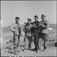 Photographie de groupe des reporters de la section ciné-photo du Service presse information (SPI) Jean Péraud, Paul Corcuff, André Lebon et Pierre Schondoerffer devant le terrain d'aviation de Na San.