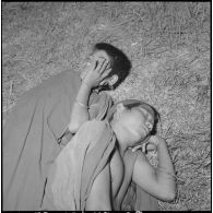 Cérémonie du sacrifice du buffle dans les hauts-plateaux montagnards : deux hommes dormant au sol pendant la veillée.