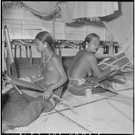 Tissage du coton par des femmes Jaraï à l'intérieur d'une habitation traditionnelle sur pilotis.