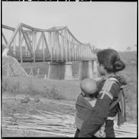 Une montagnarde et son bébé devant le pont de Sre Pok, sur la route de Saigon près de Ban Me Thuot.
