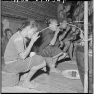Montagnards buvant l'alcool de riz à la jarre à l'intérieur d'une maison traditionnelle à l'occasion d'une célébration.