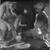 Un chasseur laotien blessé est soigné par le médecin-lieutenant Guiraud à l'intérieur d'une paillote, au cours de l'opération Frimaire dans la province de Xieng Khouang.