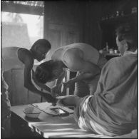 Un chasseur laotien blessé est soigné par le médecin-lieutenant Guiraud à l'intérieur d'une paillote, au cours de l'opération Frimaire dans la province de Xieng Khouang.