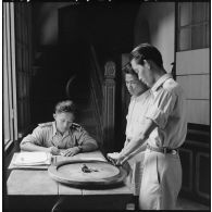 Un inspecteur de la police nationale laotienne établit l'identité judiciaire d'un suspect appréhendé tandis qu'un sous-inspecteur relève ses empreintes digitales.