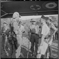 Des officiers du 2e bataillon de chasseurs laotiens (2e BCL) s'entretiennent devant un avion sanitaire venu chercher des malades.